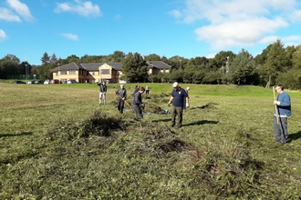 Trust volunteers and staff from Thomas Swan raking the meadow