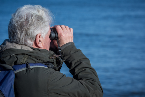 Man looking through binoculars out to sea
