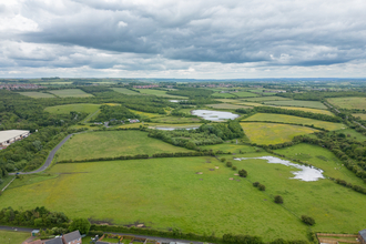 Overhead photo showing fields with nature reserve, including woodland and ponds, in distance