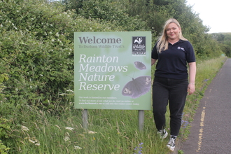 Woman standing next to Rainton Meadows entrance sign