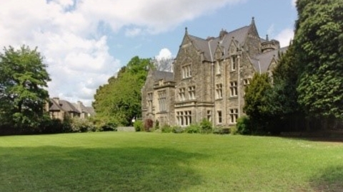 Large traditional house set in grounds of grass and mature trees