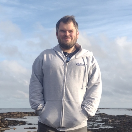 Blair Watson standing in front of sea