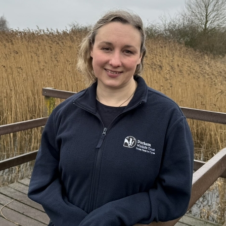 Woman standing on decked platform with reedbed in background