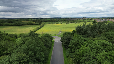 Overhead photo of tree-lined drive into nature reserve with fields at end