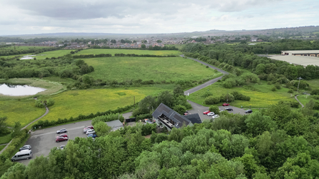 Overhead photo showing visitor centre and car park with ponds and lake in distance