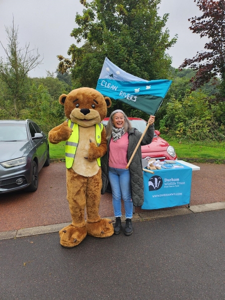 A person in otter costume standing with a women holding a banner