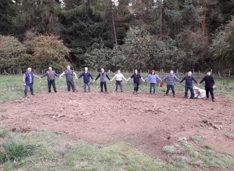 A group of people holding hands in front of woodland