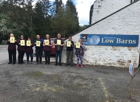 Team in front of Low Barns showing charity donation total